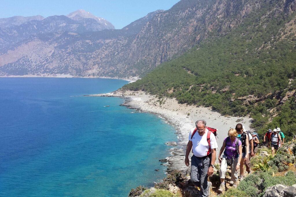 Paysage de bord de mer en Crète avec un groupe de randonneurs sur un sentier en contrebas de la mer