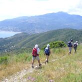 Groupe de randonneurs sur un sentier côtier avec vue sur la mer à gauche et depuis la montagne