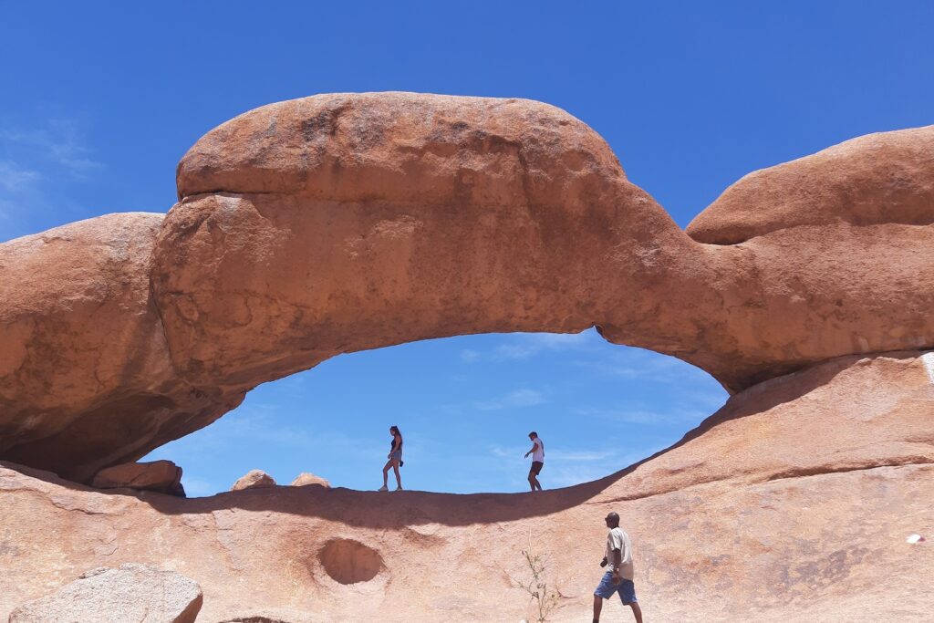 Enseble de roche formant un espace où des gens marchent, dans le désert de Namibie