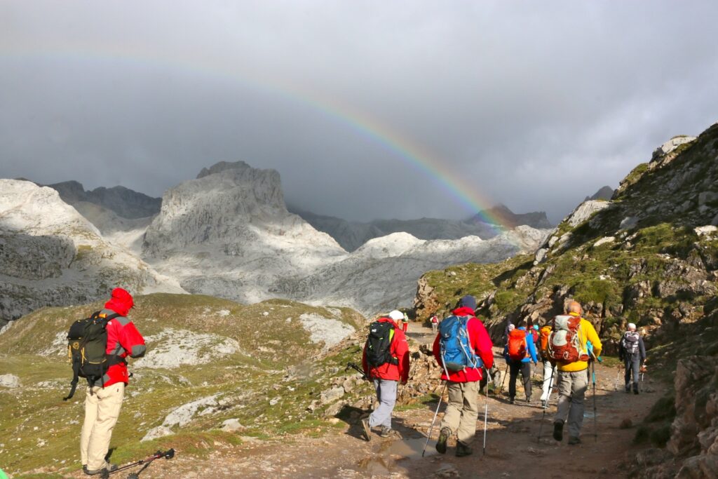 groupe de randonneurs sur un sentier dans les picos de europa avec des sommets enneigés en arrière-plan