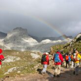 groupe de randonneurs sur un sentier dans les picos de europa avec des sommets enneigés en arrière-plan