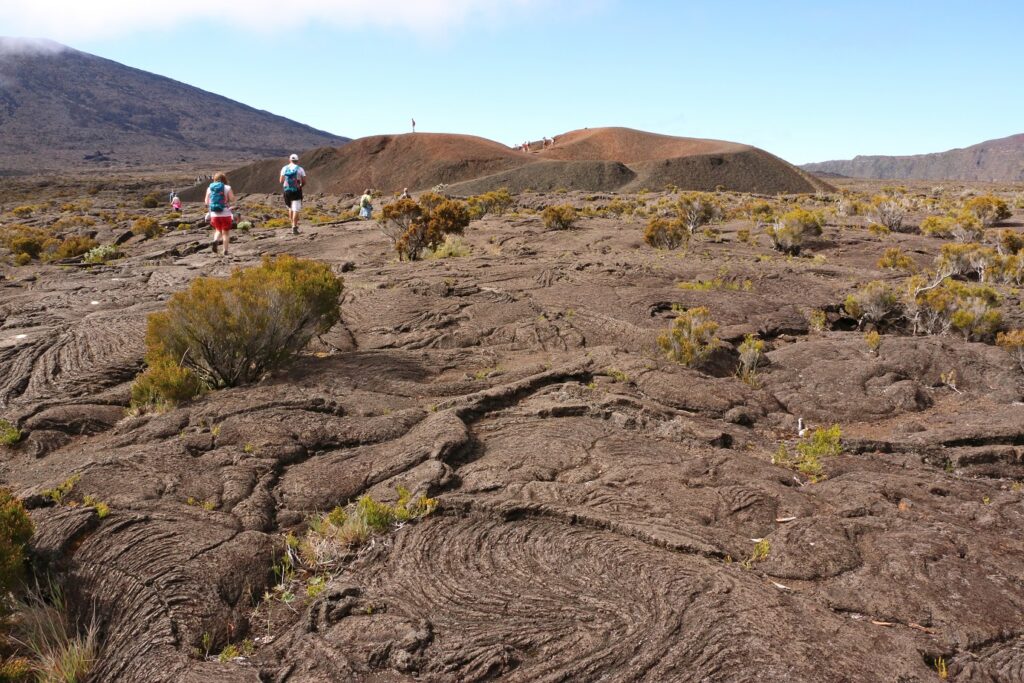 Paysage de la réunion avec un groupe de randonneurs qui marche sur des terres volcaniques