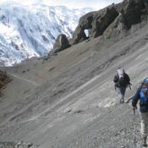 Groupe de randonneurs sur un sentier dans les Annapurnas, avec en fond des montagnes couvertes de neige