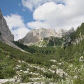 Paysage d'une vallée de montagne encadrée par des sommets, on a de la végétation au premier plan, paysage prenant place en Slovénie dans les Alpes juliennes