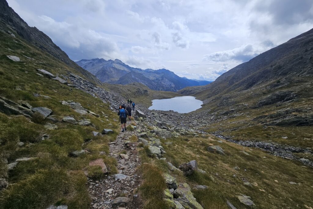 Groupe de randonneurs sur un sentier qui s'avancent, avec leur guide, vers un lac de montagne
