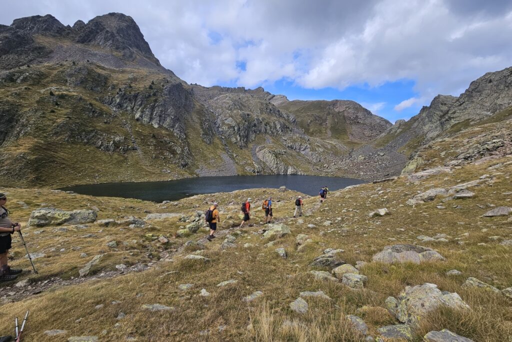 groupe de randonneurs s'avançant sur un sentier avec leur guide dans le massif des Posets, avec un lac en contrebas et des sommets