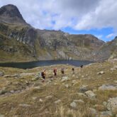 groupe de randonneurs s'avançant sur un sentier avec leur guide dans le massif des Posets, avec un lac en contrebas et des sommets