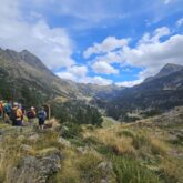 Groupe de randonneurs face au paysage montagnard estival et un panneau leur indiquant leur chemin au cours du tour des Posets avec leur guide