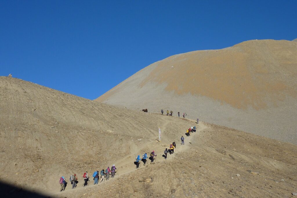 groupe de randonneurs en file indienne sur un sentier à flanc d'une montagne dans le massif des Annapurnas