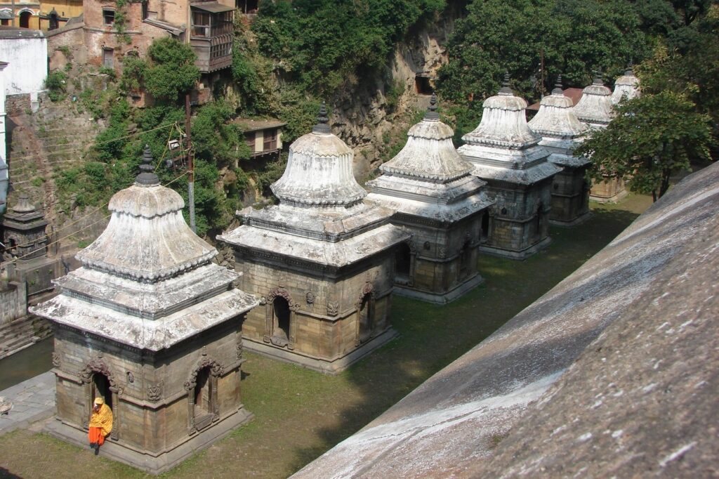 Prise de vue en hauteur d'un temple avec un moine dans le décor vêtu de vêtements orange et rouge, scène qui se déroule au Népal