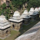 Prise de vue en hauteur d'un temple avec un moine dans le décor vêtu de vêtements orange et rouge, scène qui se déroule au Népal