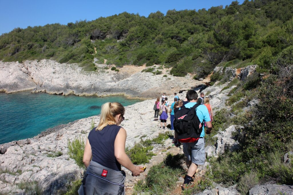 Groupe de randonneurs sur un sentier côtier avec une forêt d'un côté et de l'autre la mer