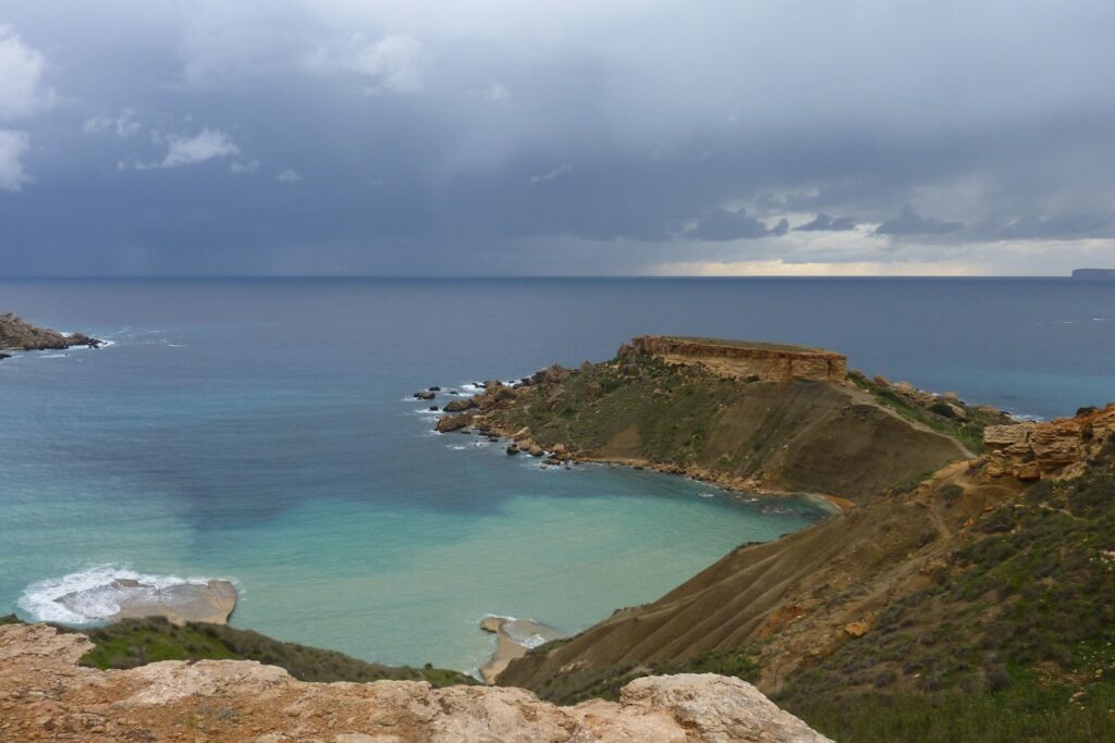 Paysage de bord de mer avec de l'eau turquoise en bord de plage et un sentier montagnard sur les hauteurs