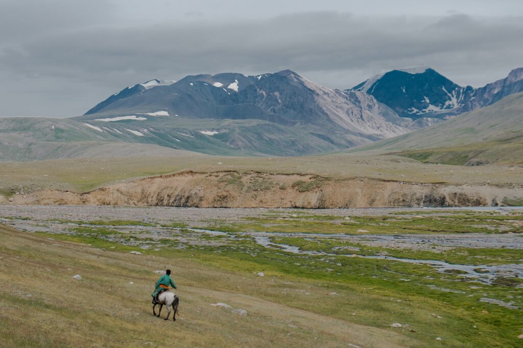 paysage de Mongolie avec un cavalier sur un sentier face aux montagnes