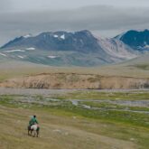 paysage de Mongolie avec un cavalier sur un sentier face aux montagnes