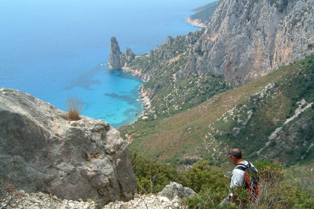 Randonneurs en train de descendre une montagne sur un sentier qui descend vers une plage