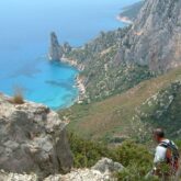 Randonneurs en train de descendre une montagne sur un sentier qui descend vers une plage