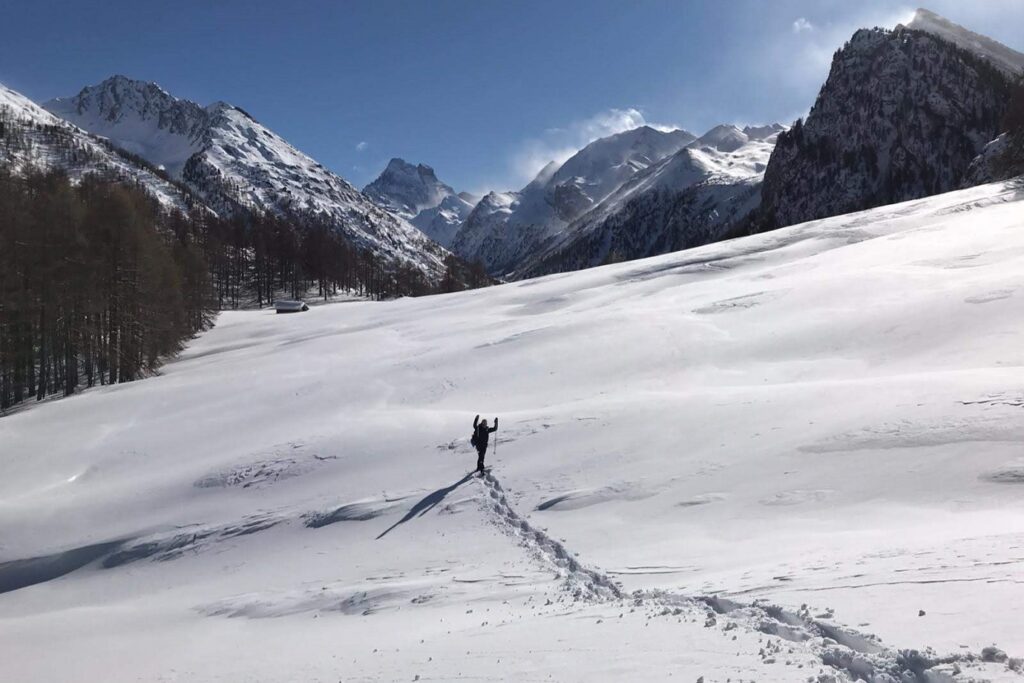Randonneur au sein de la montagne sur un sentier tracé dans la neige en raquettes lors d'un séjour accompagné d'un guide dans le massif du Queyras