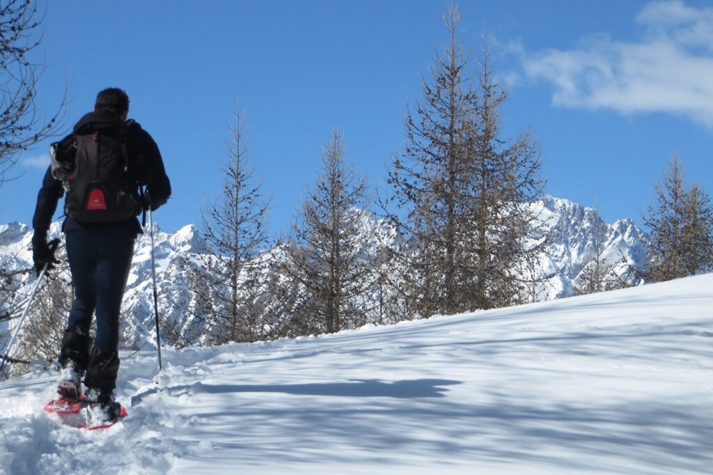 randonneurs en raquettes dans le massif du Queyras encadrés de neige, avec en fond des sommets