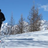 randonneurs en raquettes dans le massif du Queyras encadrés de neige, avec en fond des sommets