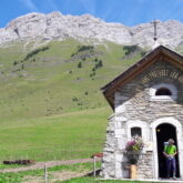 Paysage de montagne avec en fond des sommets et un bâtiment religieux