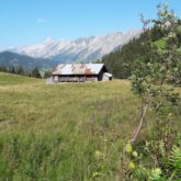 Paysage de montagne dans les Aravis, avec en fond des sommets et devant cela un bâtiment au sein de la montagne