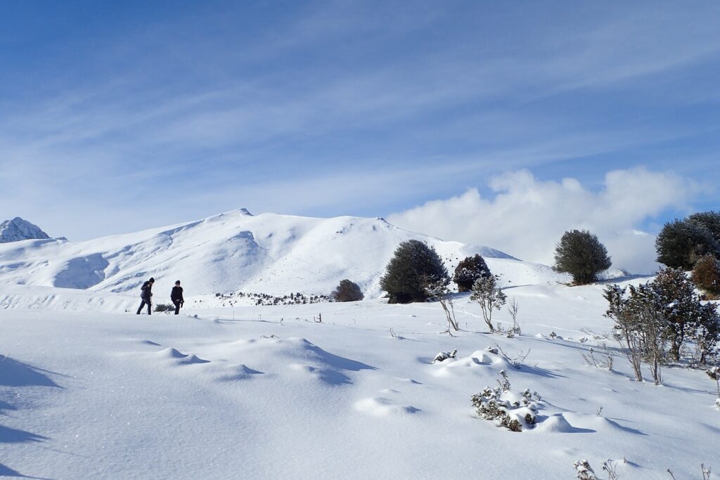 Paysage de montagne enneigé dans les Hautes Pyrénées avec des randonneurs en raquettes en fond