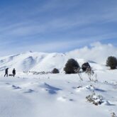 Paysage de montagne enneigé dans les Hautes Pyrénées avec des randonneurs en raquettes en fond