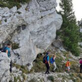 Groupe de randonneurs sur un sentier dans le Vercors encadré de roches et d'arbres