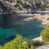 Paysage de bord de mer avec des rochers et de l'eau turquoise, encadré de falaises