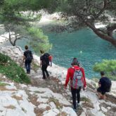 Groupe de randonneurs avec leur guide sur un sentier de randonnée, avec en contrebas la mer