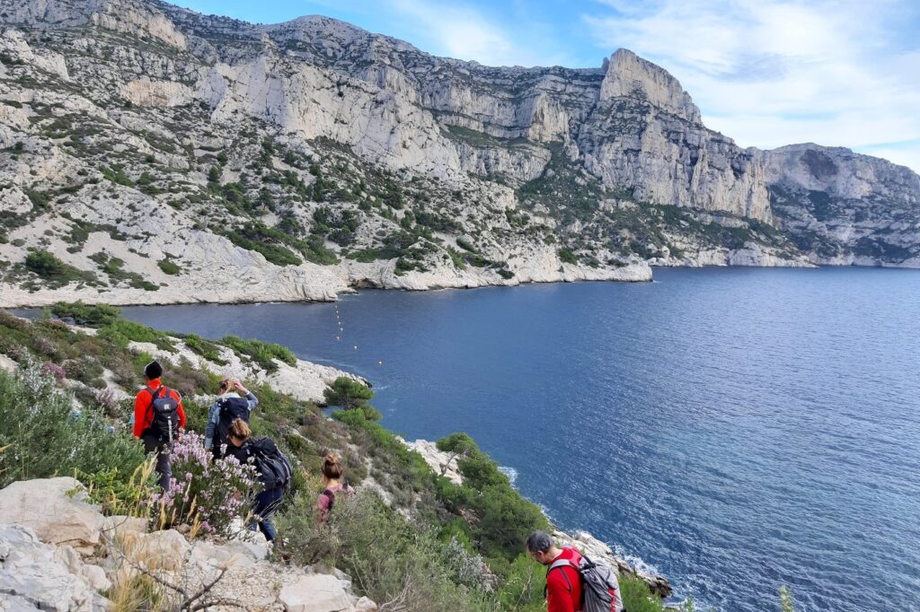 Groupe de randonneurs avec leur guide sur un sentier, flanc d'une falaise, avec la mer en contrebas