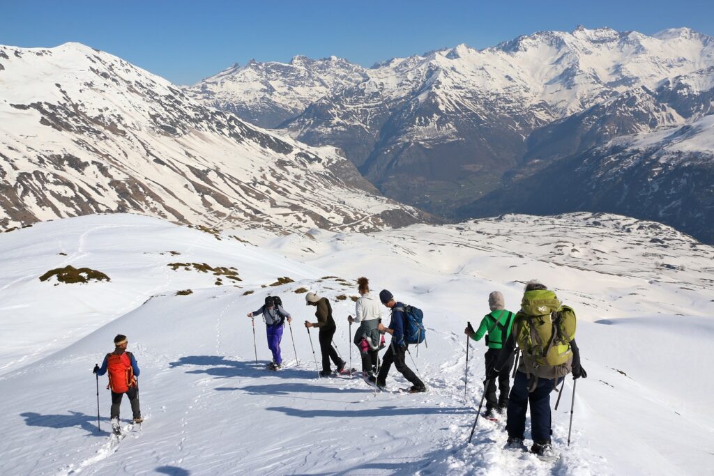 Groupe de randonneurs avec leur guide sur les sentiers de raquettes entre Cauterets et Gavarnie, avec en fond une vallée surplombée par des sommets enneigés