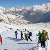 Groupe de randonneurs avec leur guide sur les sentiers de raquettes entre Cauterets et Gavarnie, avec en fond une vallée surplombée par des sommets enneigés