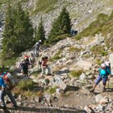 Groupe de randonneurs sur un sentier de randonnée avec beaucoup de cailloux en train de monter avec leur guide lors du tour du mont Blanc sud