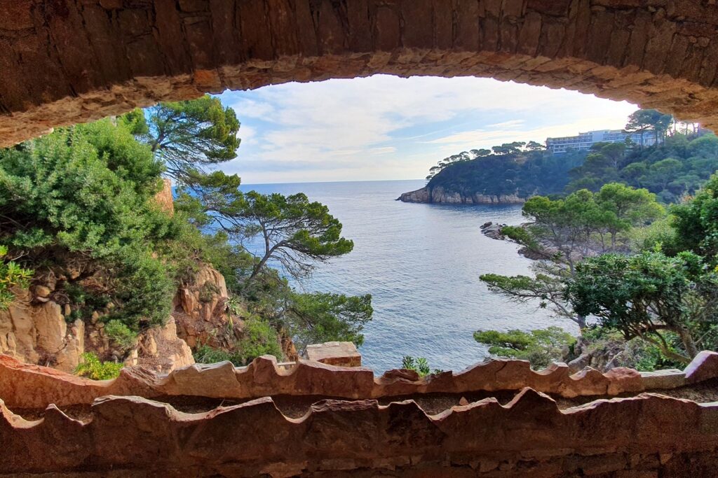 Paysage observé à travers une fenêtre de pierre en Costa Brava, avec un paysage idyllique avec des pins parasols et la mer aux couleurs magnifiques