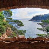 Paysage observé à travers une fenêtre de pierre en Costa Brava, avec un paysage idyllique avec des pins parasols et la mer aux couleurs magnifiques