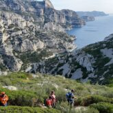 Groupe de randonneurs sur un sentier de randonnée en train de descendre à flanc de montagne vers les calanques.
