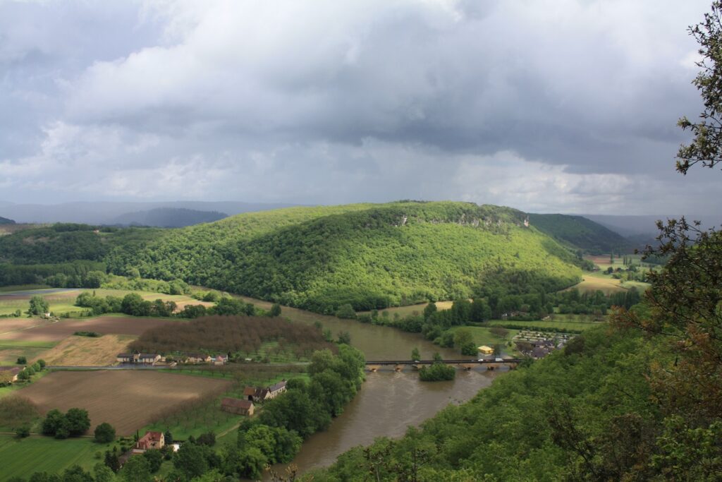 Paysage vu de haut de la campagne en Dordogne, avec des collines couvertes d'arbres ainsi qu'un cours d'eau qui passe au milieu