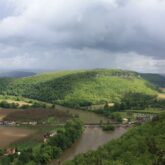 Paysage vu de haut de la campagne en Dordogne, avec des collines couvertes d'arbres ainsi qu'un cours d'eau qui passe au milieu