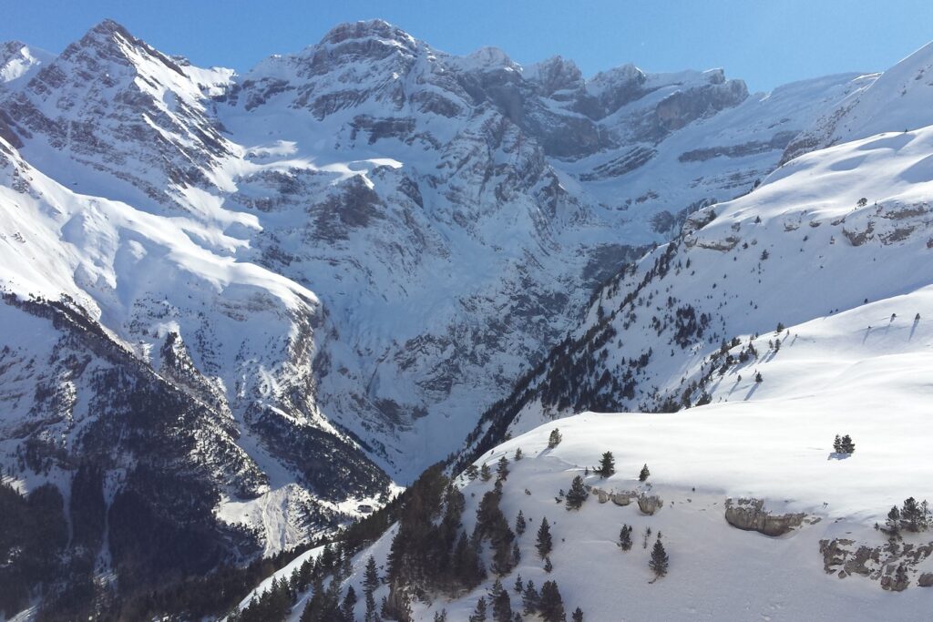 Paysage de montagne avec des sommets et des vallées couverts de neige, avec en fond des sommets
