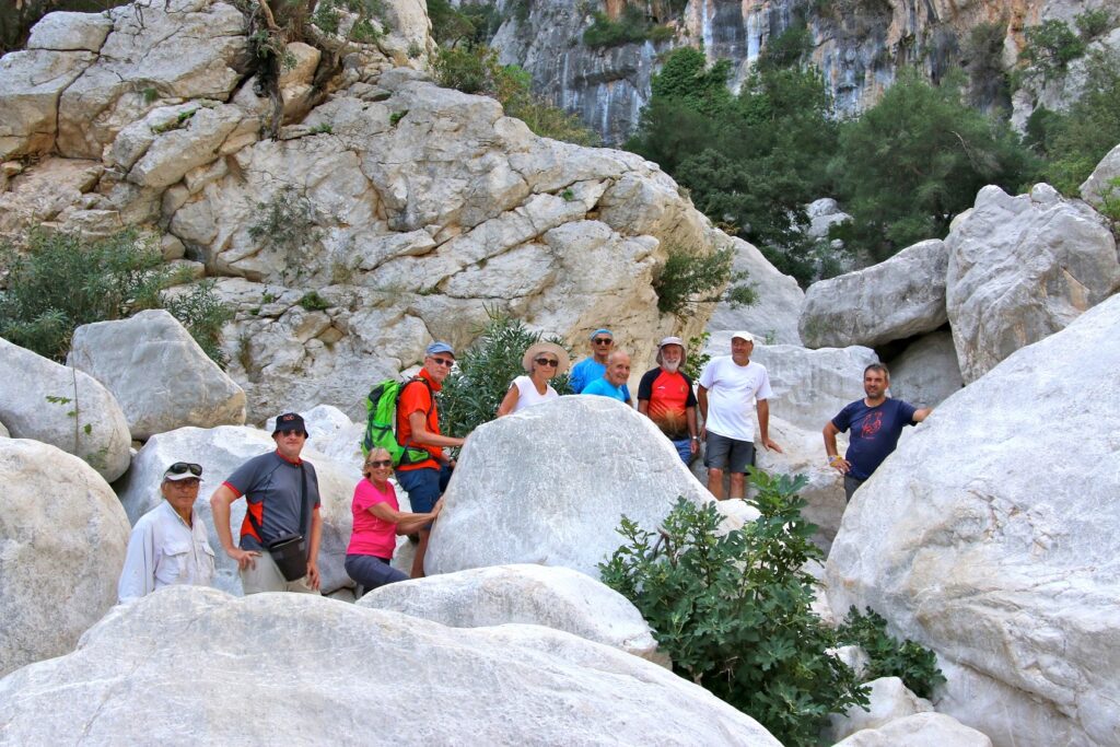 Groupe de randonneurs sur un sentier à travers des rochers blancs en bord de mer en Sardaigne