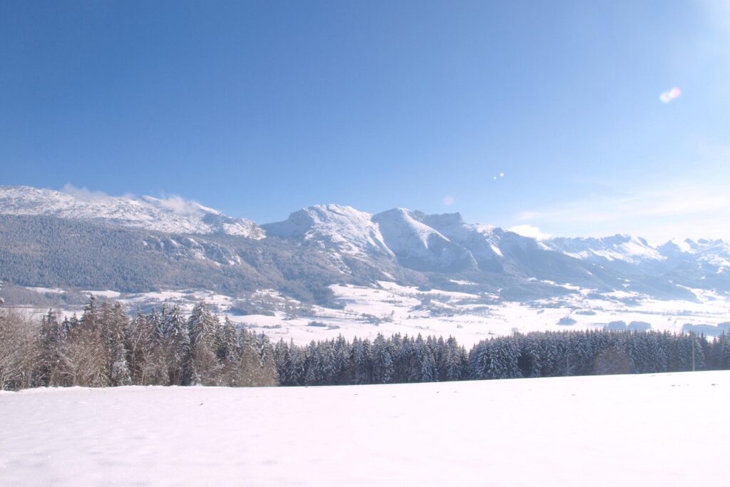 Paysage enneigé dans le vercors avec des sommets en fond et un grand plateau couvert de neige au premier plan