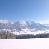 Paysage enneigé dans le vercors avec des sommets en fond et un grand plateau couvert de neige au premier plan