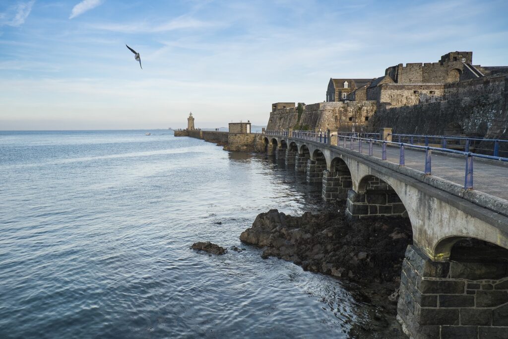 Paysage jersey, une des îles au large de la Bretagne avec un pont sur la droite et des habitations et l'océan sur la gauche
