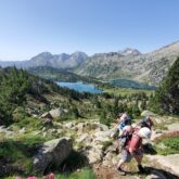 Groupe de randonneurs sur un sentier de randonnée avec en fond un lac de montagne et des sommets appartenant au massif du Néouvielle