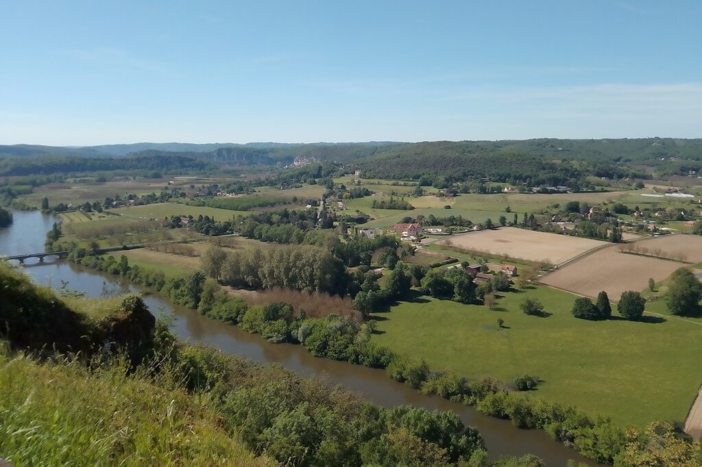 Paysage vu en hauteur d'une vallée en Dordogne avec des champs ainsi qu'un cours d'eau