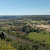 Paysage vu en hauteur d'une vallée en Dordogne avec des champs ainsi qu'un cours d'eau