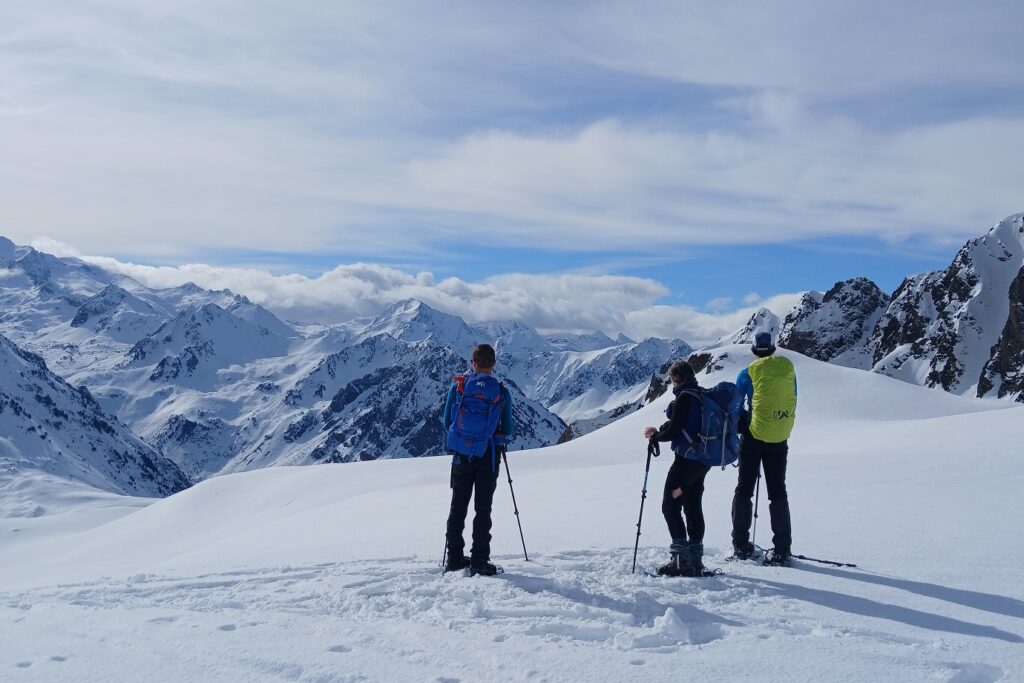 Groupe de randonneurs face à la vue lors d'une randonnée en raquettes avec leur guide dans les hautes Pyrénées entre le Néouvielle et Cauterets