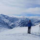 Groupe de randonneurs en raquettes avec leur guide sur un sentier de randonnées en montagne face à la vue
